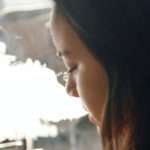 young girl with brown hair and smoke coming out of her mouth, side profile