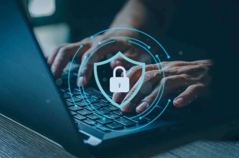 two hands typing on a laptop with a blue circle layered over. The circle has a lock and a shield inside it.